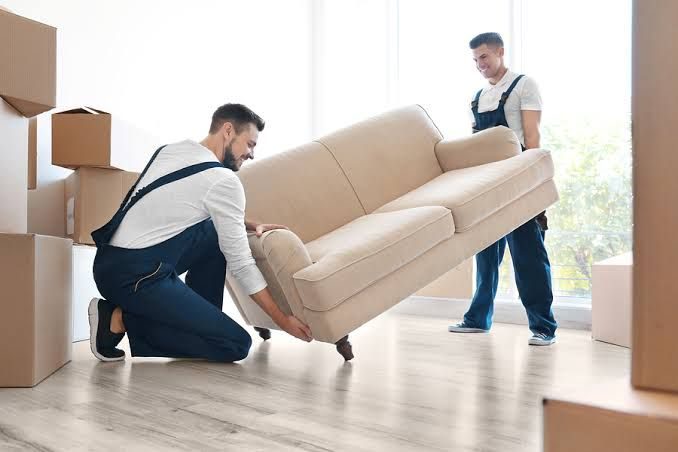 Two crew members lifting a sofa for removal