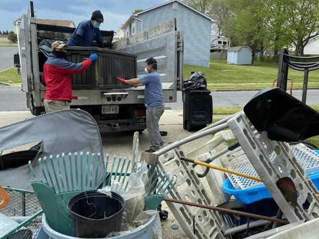 Crew loading old household items into a removal truck in a driveway