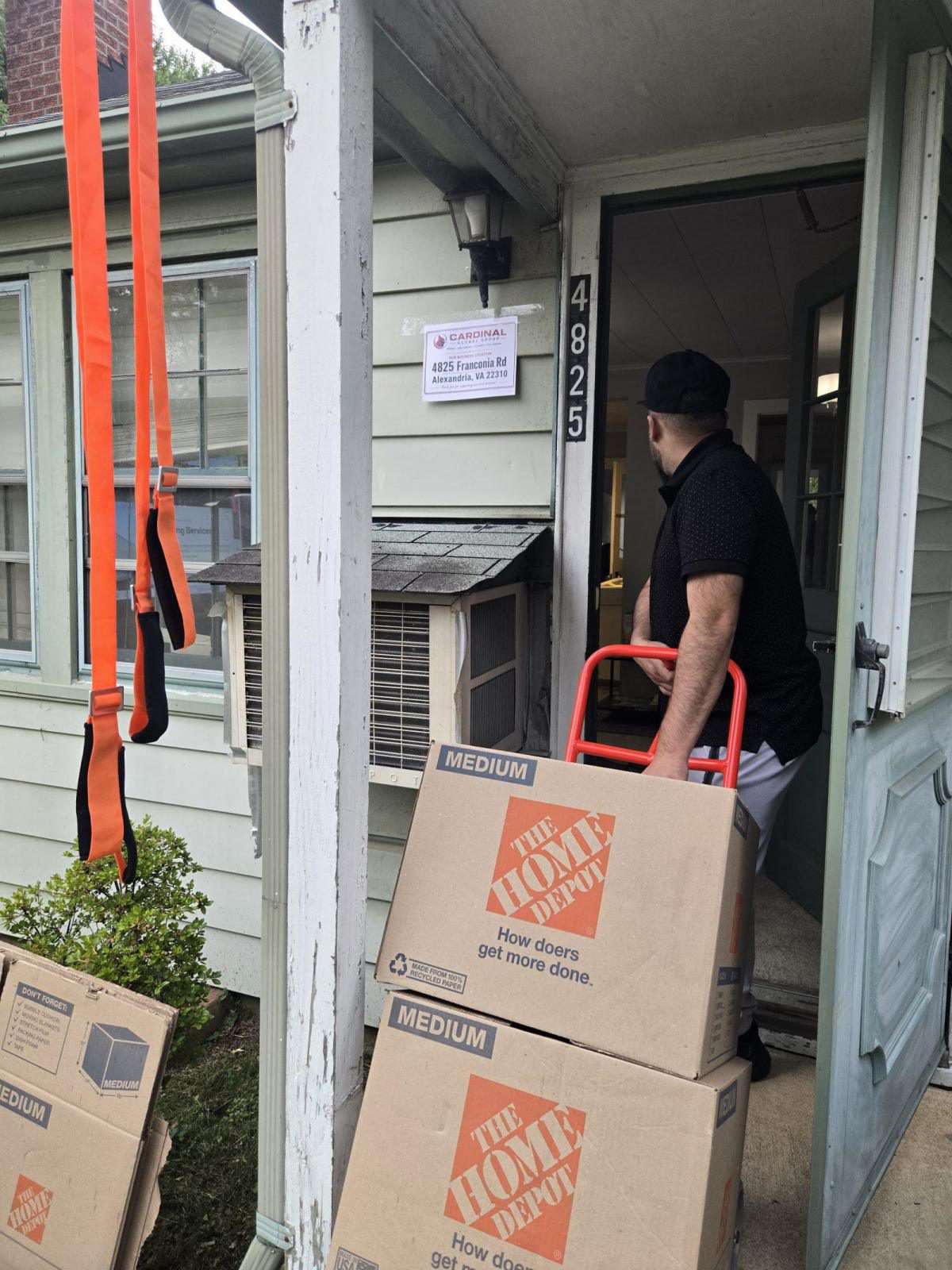 Crew member wheeling boxes on a hand truck into a building entrance