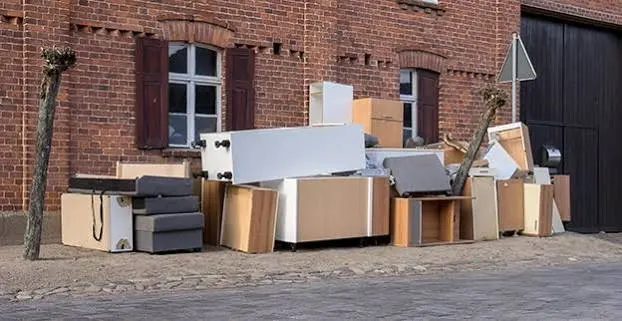 Store shelving, cabinets and display fixtures stacked outside a building